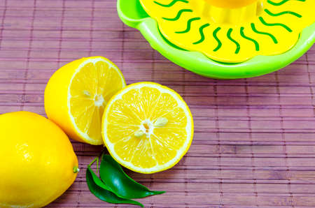 Halved lemons and a colander on a purple bamboo surfaceの写真素材