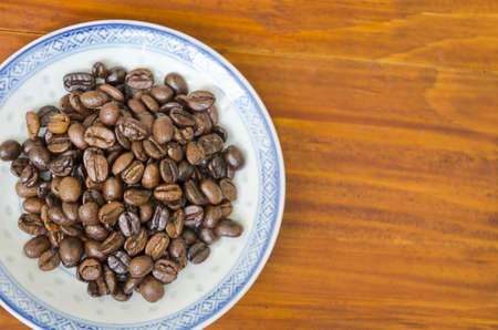 Coffee beans on a old plate on a wooden tableの写真素材