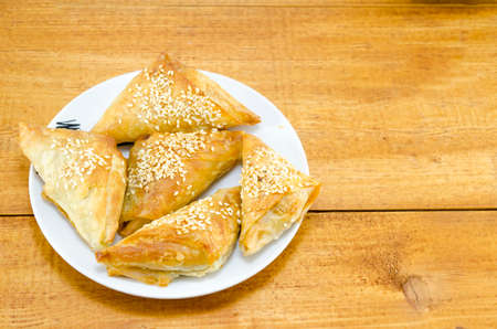 Homebaked triangle shaped meat pie on a white plate shot on a wooden tableの写真素材