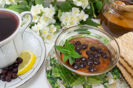 Chokeberry tea in a porcelain cup on a flower decorated tableの写真素材