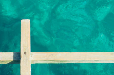 Abstract photo of a wooden board angainst clear sea waterの写真素材