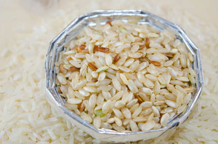 Rice in an aluminum bowl on a table covered with riceの写真素材