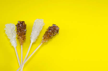 Two sugar sticks containg white and brown sugar with yellow backgroundの写真素材