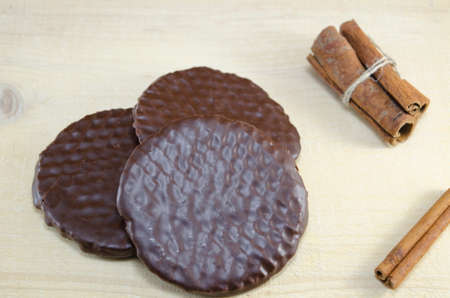 Chocolate biscuits on a red plate with cinnamon sticks