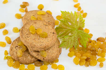Integral cookies and yellow raisins with a large green flower on whiteの写真素材