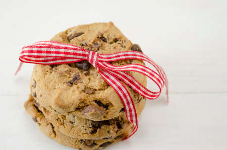 Chocolate chip cookies tied together with a red ribbon on whiteの写真素材