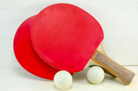 Two red table tennis rackets and balls on a wooden tableの写真素材