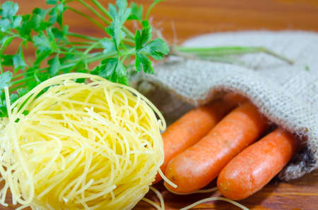 Homemade noodles, carrots and parsley on a tableの写真素材