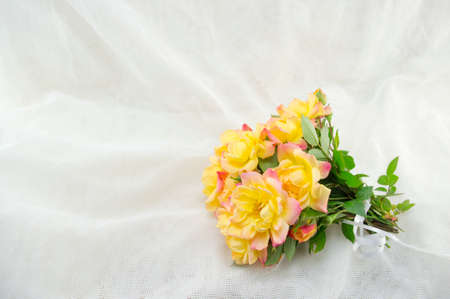 Bouquet of yellow roses on a white silken sheetの写真素材