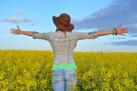 Girl posing with a hat in a field of yellow flowersの写真素材