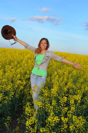 Girl posing with a hat in a field of yellow flowersの写真素材