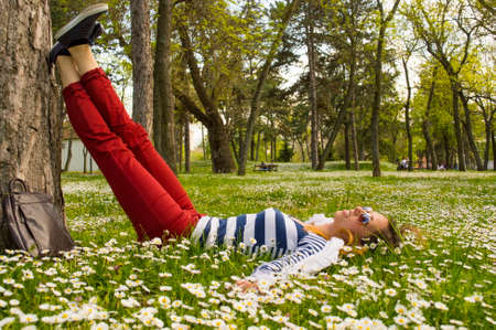Bunette girl lying in the grass full of flowersの写真素材