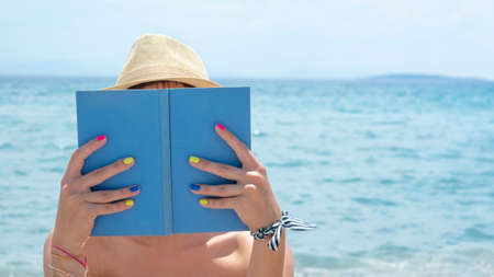 Girl reading a book on the beachの写真素材
