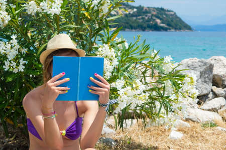 Girl reading a book in shade near the beachの写真素材