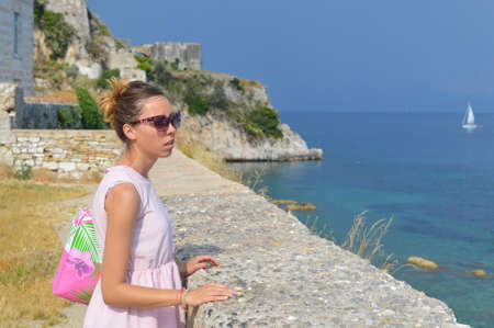 Girl looking at the sea from the new fortress in kerkyra wearing pink dress and sunglassesの写真素材
