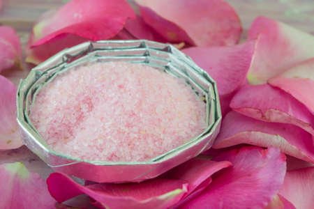 Pink aromatic bath salt on a table decorated with rose petalsの写真素材