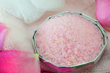 Pink aromatic bath salt on a table decorated with rose petalsの写真素材