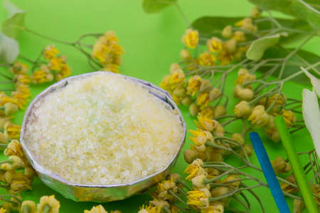 Gren bath salt decorated with linden flowers on a green backgoundの写真素材