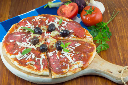 Homebaked pizza sliced with vegetables on a wooden tableの写真素材