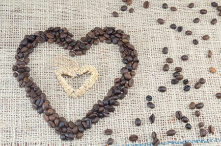 Heart shaped coffee grains placed on a coffee bag with scattered coffee grainsの写真素材