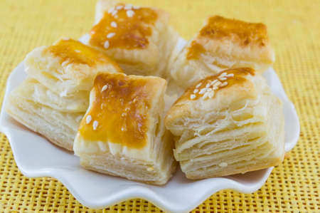 Homebaked puff pastry with sesame on a yellow backgroundの写真素材