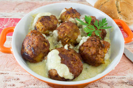 Homemade meatballs served in an orange bowl with corn bread on a colorful tableの写真素材