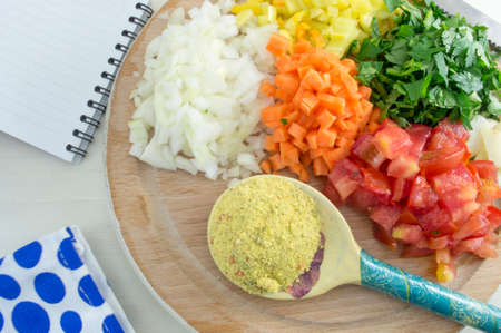 Colorful sliced vegetables and spice in a wooden spoon ready for cooking