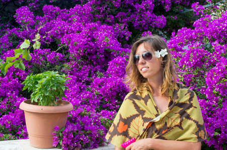 Young girl with sunglasses and a flower in her hair surrounded by beautiful purple flowersの写真素材