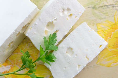 Homemade sliced white cheese and parsley on a decoupage decorated tableの写真素材