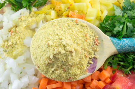 Wooden spoon with spices and colorful sliced vegetables on the board ready for cookingの写真素材
