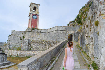 Girl looking at the big old clock in a new  fortress at Corfu islandの写真素材