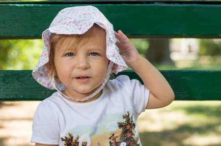 Adorable one year old baby portrait in a park wearing funny hatの写真素材