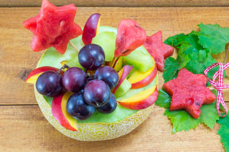 Fresh attractive colorful fruit salad served in a fresh melon on a wooden tableの写真素材
