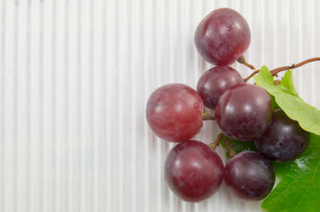 Fresh natural red grape on white textured cardboardの写真素材