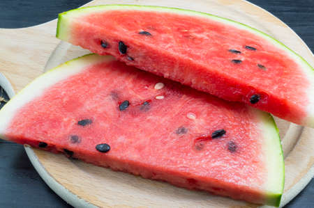 Sliced fresh watermelon on a black wooden table