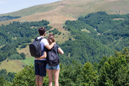 Couple of hikers with backpacks standing at viewpoint and enjoying a valley view. Couple's shared activityの写真素材