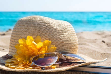 Straw hats, sunglasses and a book on the beachの写真素材