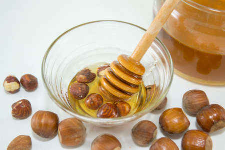 Nuts and honey in  a glass dish next to a glass with honey. Healthy dessertの写真素材