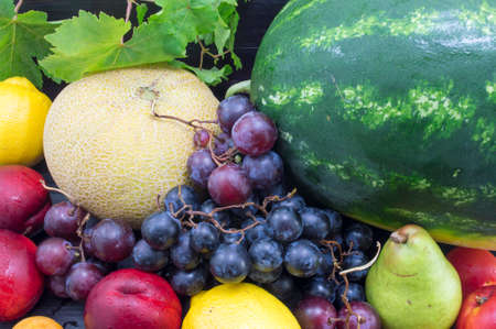 Various summer fruit on the dark wooden table. Healthy fruit backgroundの写真素材