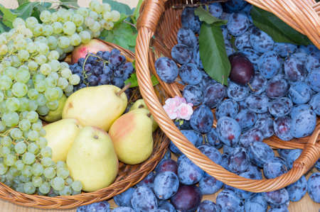 Fresh fruit baskets. Fresh plums, grapes and pears in wooden basketsの写真素材