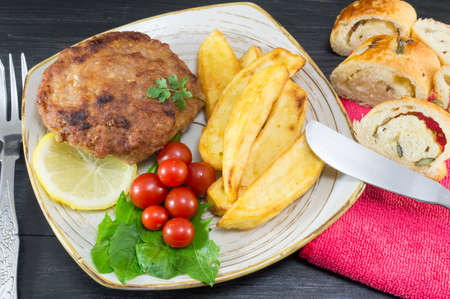 Hamburger steak with potatoes, cherry tomatoes and olive bread served  on a plateの写真素材