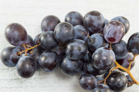Cluster of grapes on white wooden tableの写真素材