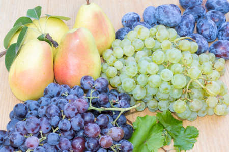 Grape, pears and plums on a wooden tableの写真素材