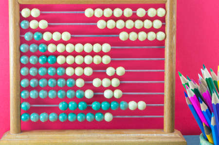 Old calculator and bunch of colored pencils against red backgroundの写真素材