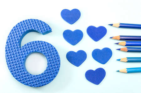 Learning the number 6. Blue number six and pencils on black paper backgroundの写真素材