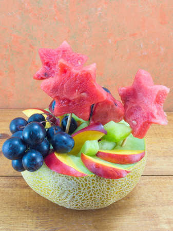Fresh attractive colorful fruit salad served in a fresh melon on a wooden tableの写真素材
