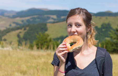 Happy girl hiker eating a doughnut while on hikingの写真素材