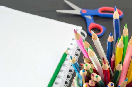 Working with colored pencils. Colored pencils in the jar with a notebook in the backgroundの写真素材
