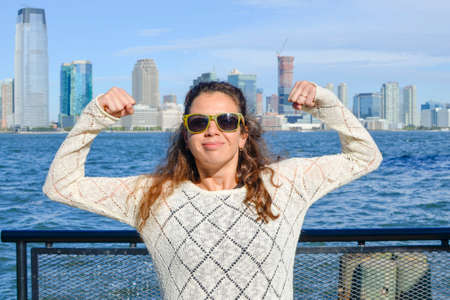 Girl pumping muscles against Manhattan view on a sunny dayの写真素材