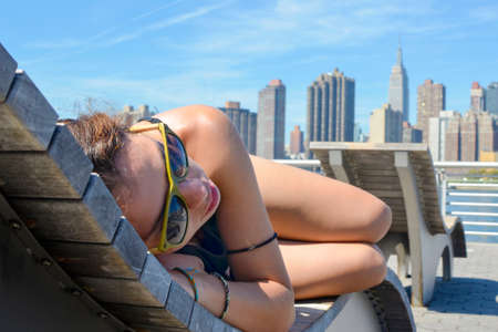 Girl enjoying Manhattan view lying on the wooden sunbedの写真素材